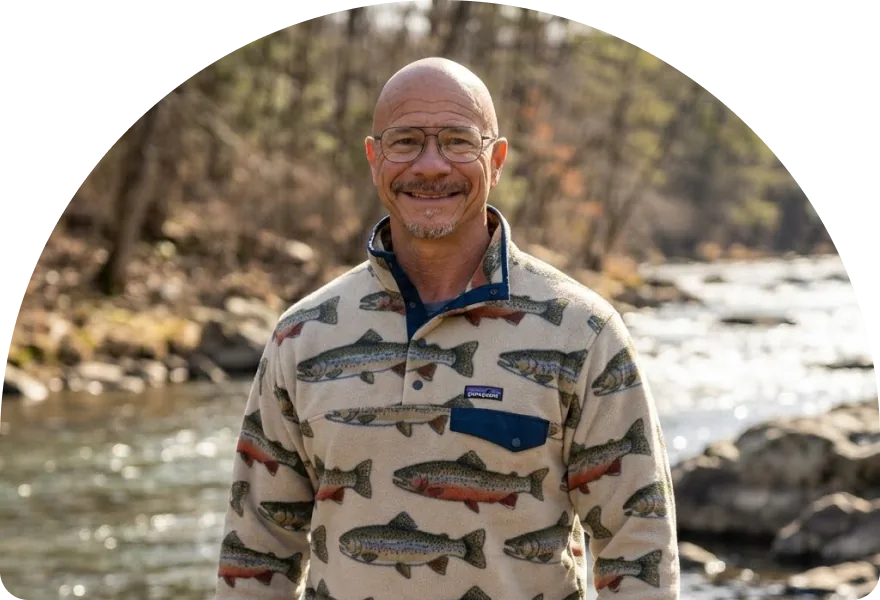 Donnie, the founder of Alaska Intervention Specialists, smiling beside a river.