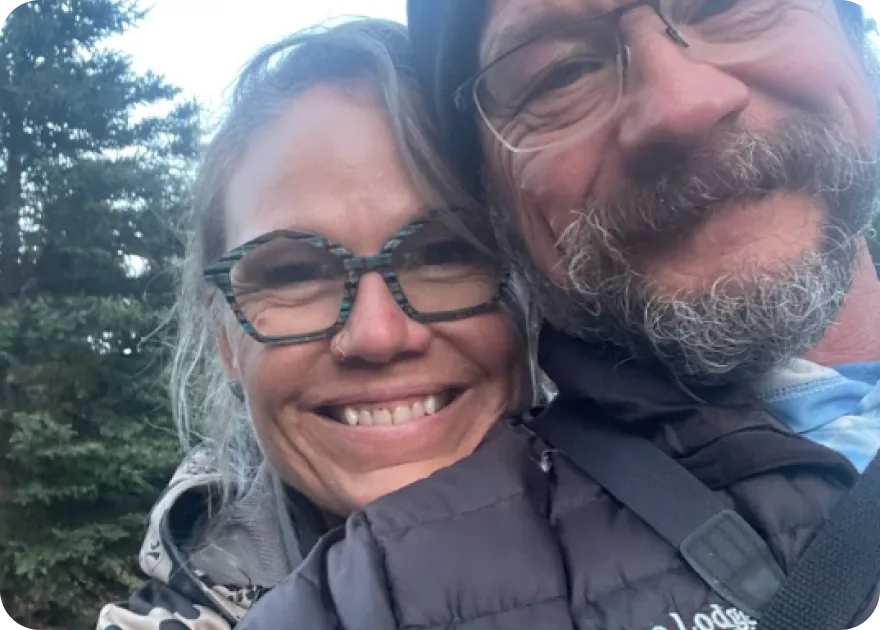 A smiling woman and man photographed together outdoors in warm jackets.